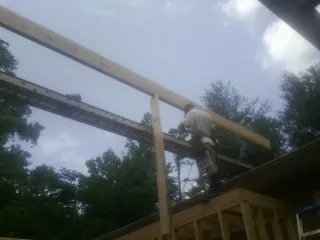 Carpenter setting a ridge beam over a new addition frame — Ice Dam Removal by Roofing Brothers in Lyndeborough