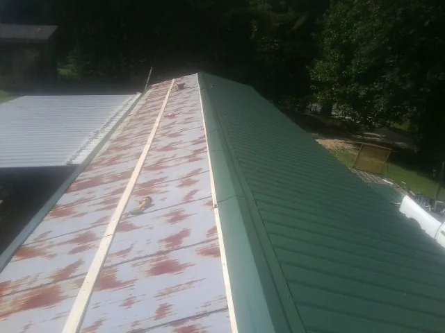 Old rusted panels beside newly installed green metal roofing — Wind Damage Roof Repair by Roofing Brothers in Lyndeborough