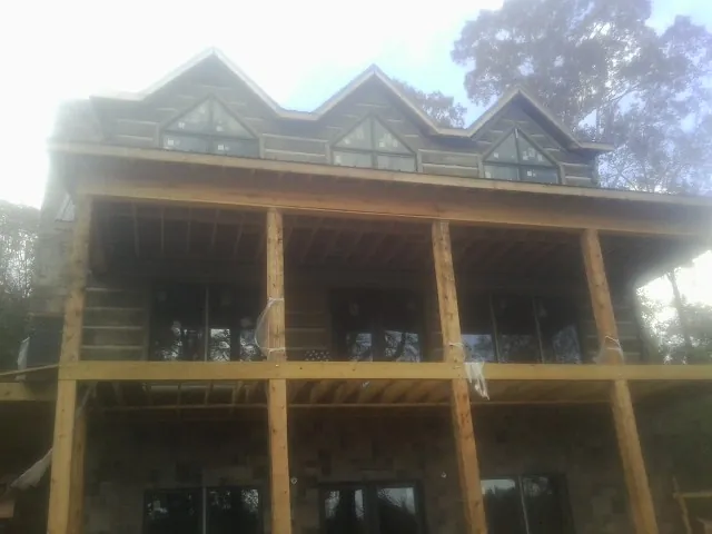 Dormers and porch framing on a large log home under construction — Roof Coating work by our crew in Lyndeborough
