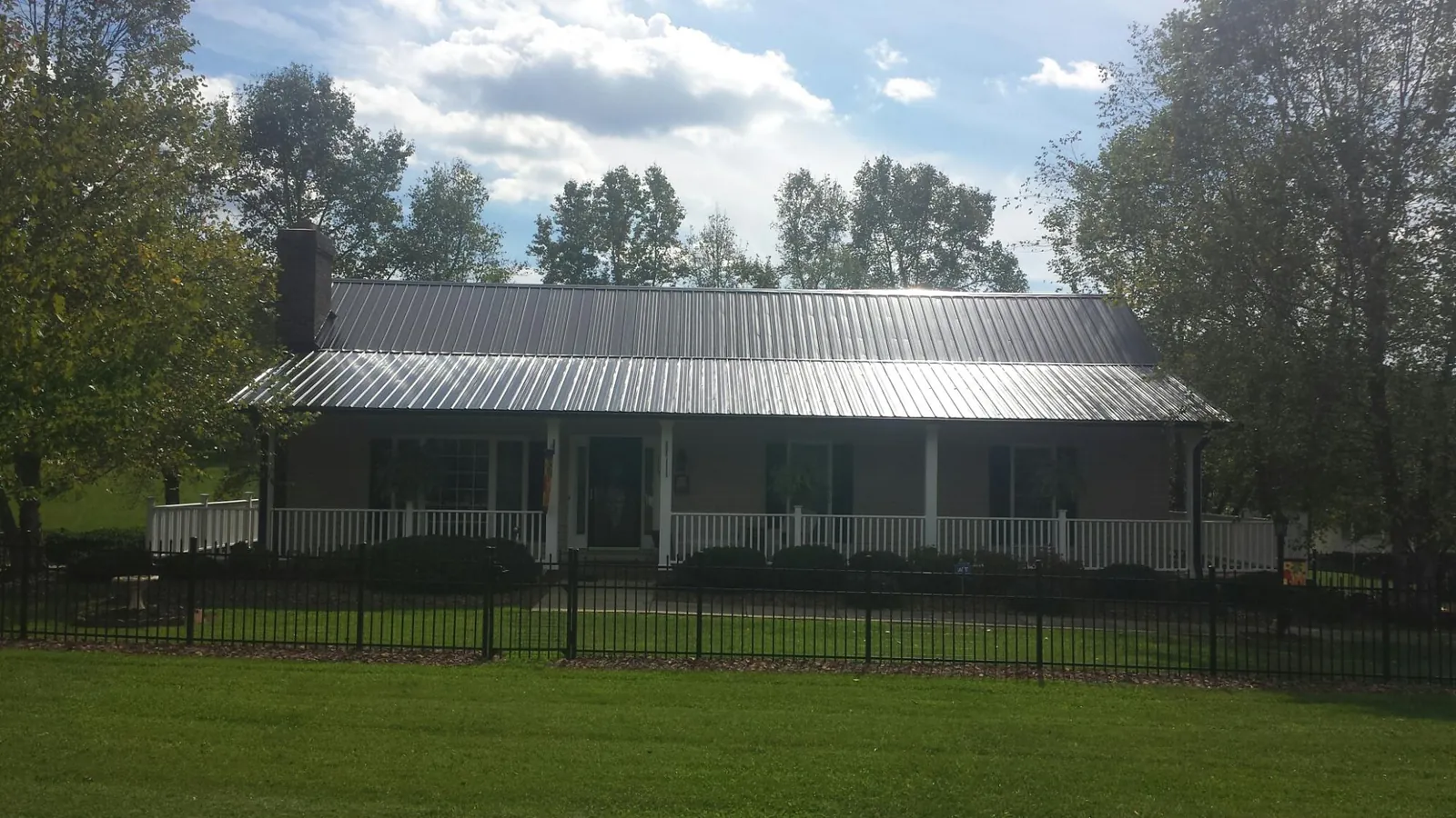 Gray metal roof on a brick ranch with a full width front porch — Gutter Guard Installation work by our crew in Lyndeborough