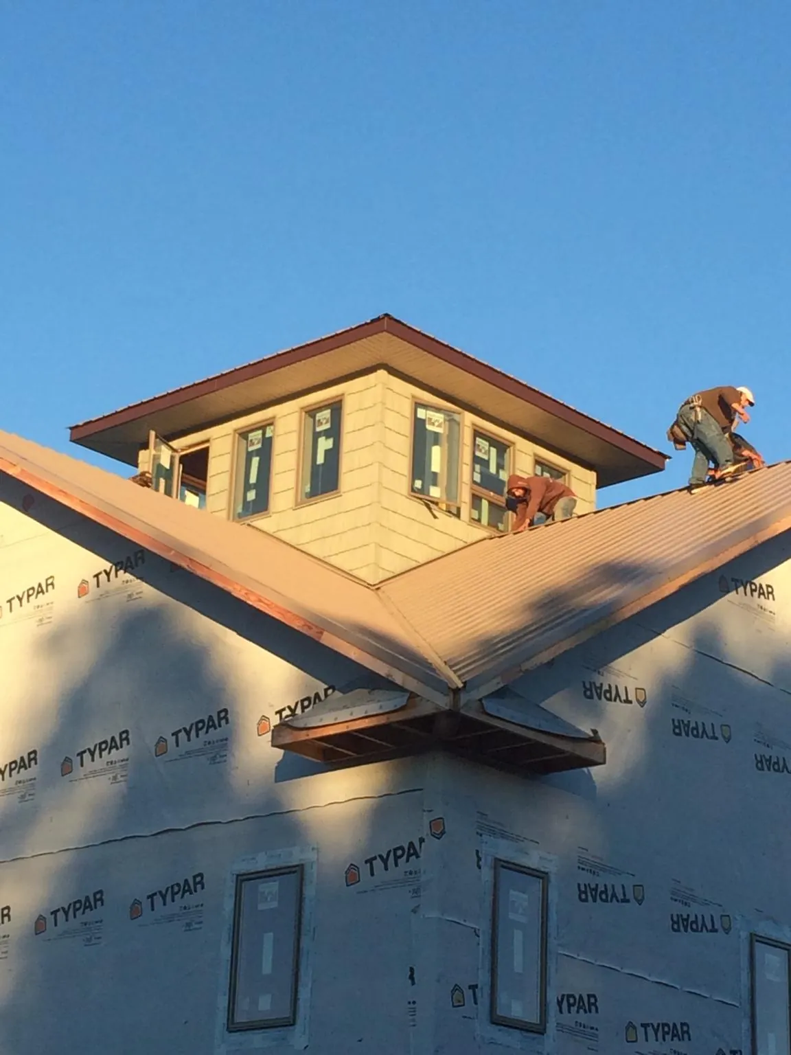 Roofers working around a rooftop cupola on a new metal roof at sunset — Roof Waterproofing in Lyndeborough by Roofing Brothers